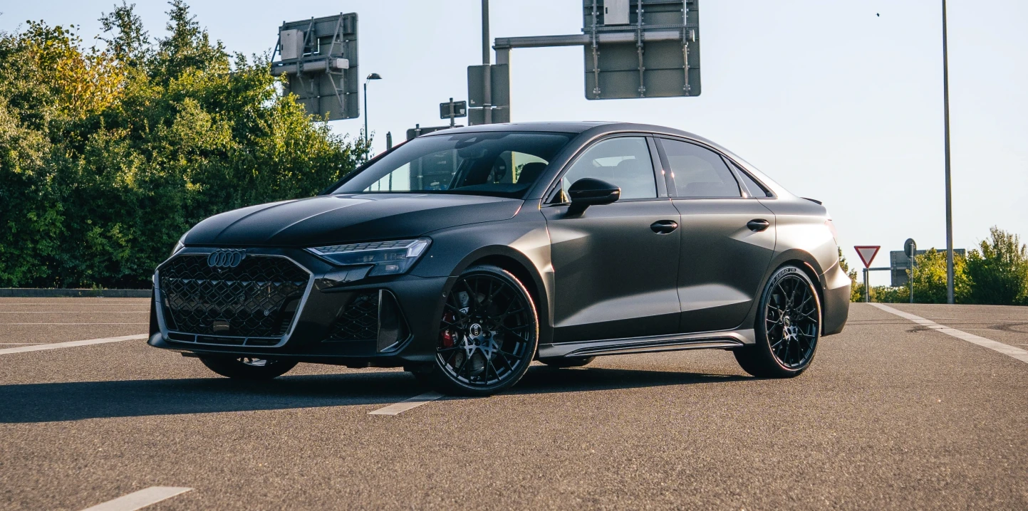 Audi RS3 2025 in schwarz matt seitlich frontal auf einem Parkplatz